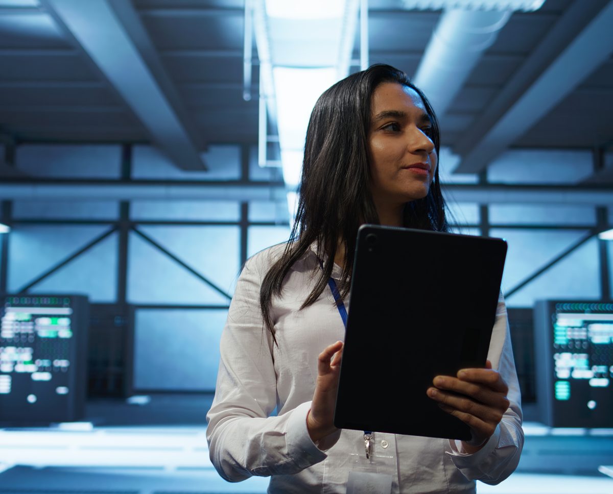 A data warehouse engineer holding a tablet in a data center
