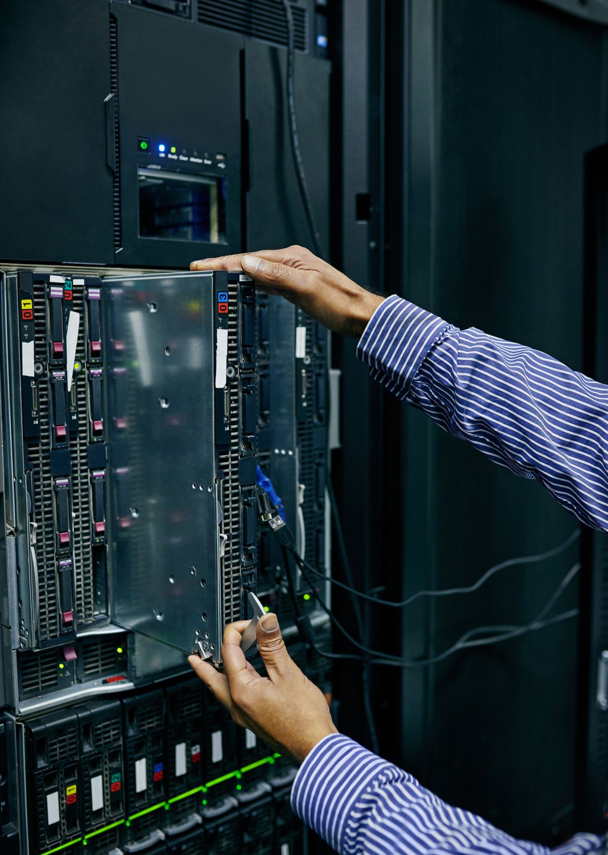 Hands installing a server blade in a data center rack