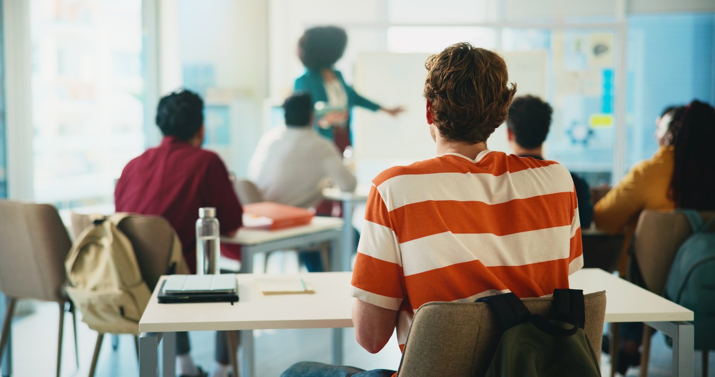 Students seated in a lecture hall while an instructor presents at the front